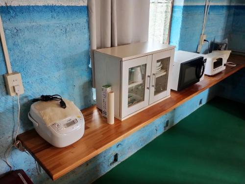 a counter with a microwave and a television on it at Unwind DAY OFF Nagamo in Yaese