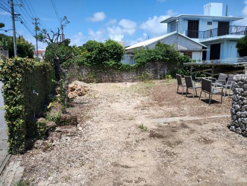 a yard with chairs and a fence and a house at Unwind DAY OFF Nagamo in Yaese