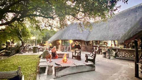 two people sitting around a fire in front of a building at Roy's Rest Camp in Groutfontein