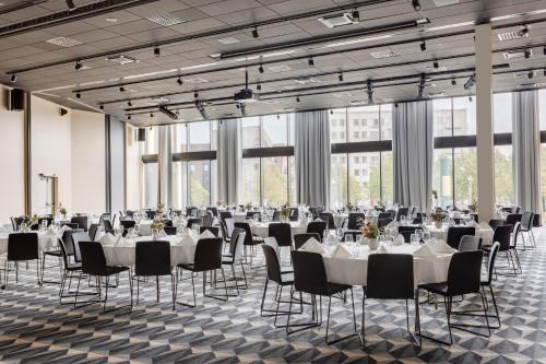 a banquet hall with white tables and chairs and large windows at Clarion Hotel Karlatornet in Gothenburg