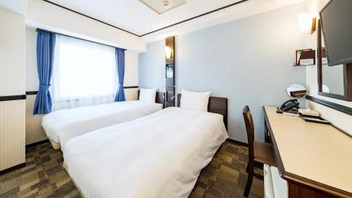 a hotel room with two beds and a television at Toyoko Inn Ise Matsusaka Ekimae in Matsuzaka