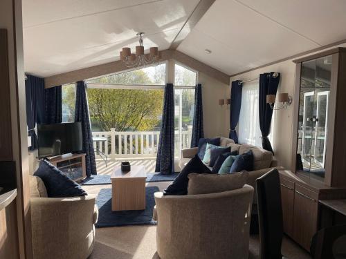 a living room with a couch and chairs and a television at Stunning 2 Bed Caravan on the Lake Front in Gloucestershire
