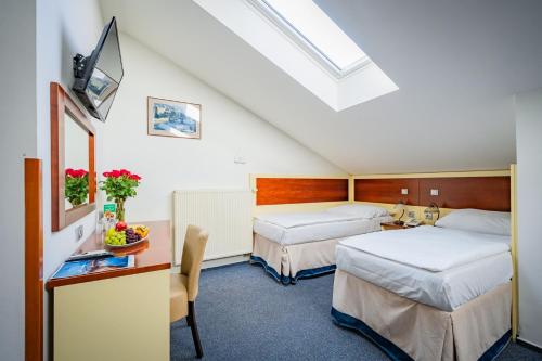 a hotel room with two beds and a desk with a tv at Hotel Atos in Prague