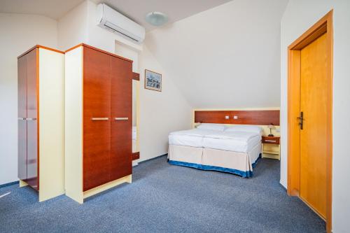 a bedroom with a bed and a wooden cabinet and a bed at Hotel Atos in Prague