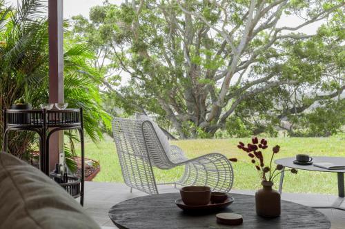 a patio with a table and chairs and a tree at Tranquil Byron Bay Villa, Hinterland views - Vue 3 in Ewingsdale