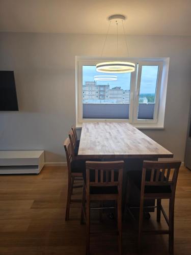 a dining room table with chairs and a large window at Spacious and cozy apartment in Tartu in Tartu