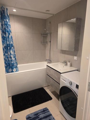 a bathroom with a tub and a sink and a washing machine at Spacious and cozy apartment in Tartu in Tartu