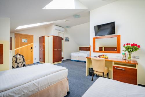 a hotel room with two beds and a desk at Hotel Atos in Prague