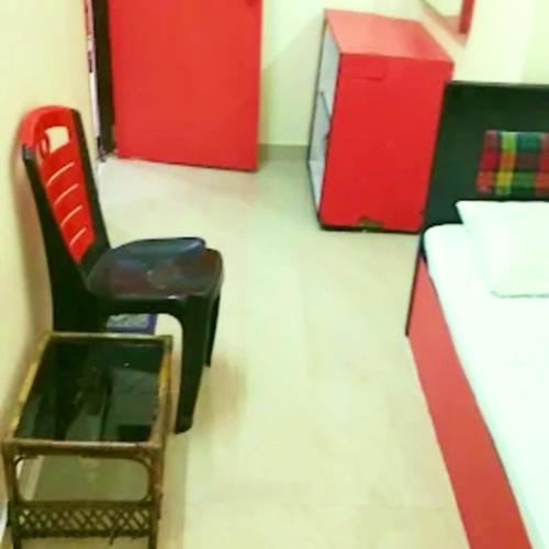 a room with a chair and a desk and red cabinets at Hotel Pine City in Shillong