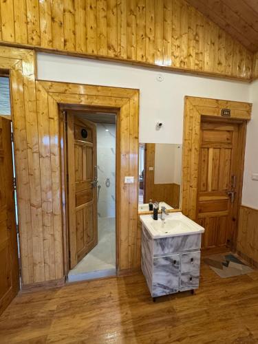 a bathroom with a sink and a mirror and wooden walls at The Highgrove House, Manali in Haripūr