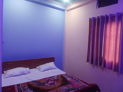 a bedroom with a bed with purple walls and a window at Tridev paying guest house in Varanasi