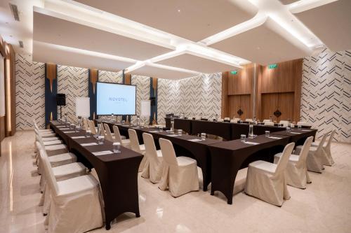 a large conference room with a long table and white chairs at Novotel Bogor Golf Resort in Bogor