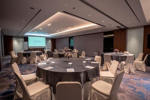 a conference room with tables and chairs and a screen at Novotel Bogor Golf Resort in Bogor
