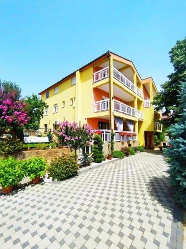 a large yellow building with flowers in front of it at Rooms Ivana in Međugorje