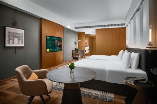 a hotel room with a large bed and a table at MaxX by Steigenberger Harbour-view Qingdao in Qingdao