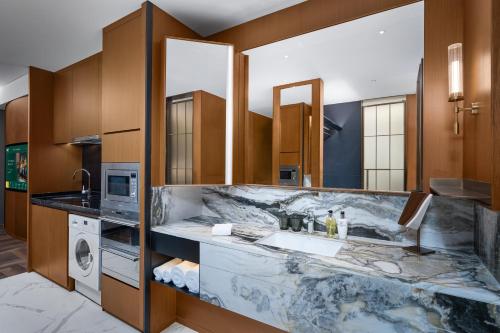 a bathroom with a marble counter and a sink at MaxX by Steigenberger Harbour-view Qingdao in Qingdao
