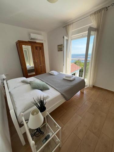 a bedroom with a large bed and a large window at Holiday Home Aqua in Šmrika