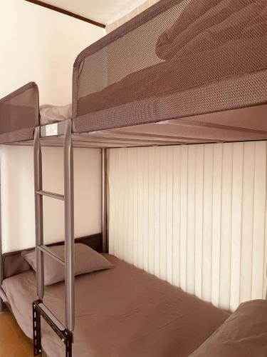 a bunk bed with a ladder on the bottom bunk at CCCOFFEE HOSTEL Kobe in Kobe