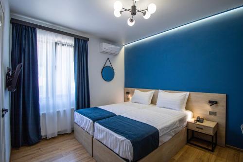 Un dormitorio azul con una cama y una pared azul. en Hotel Tvisi Tbilisi, en Tiflis