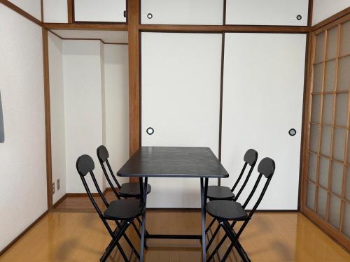 una mesa negra y sillas en una habitación en Dogo Comfort Stay 201, en Matsuyama