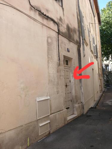 une porte sur le côté d'un bâtiment avec une flèche rouge dans l'établissement Appartement Avignon Centre ville intra muros, à Avignon