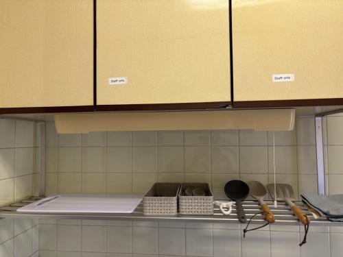 Una cocina con gabinetes amarillos y utensilios en un estante. en Dogo Comfort Stay 201, en Matsuyama