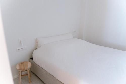 a small bedroom with a white bed and a wooden stool at La Brise Marine in Ostend