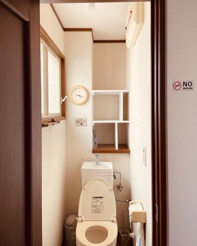 a small bathroom with a toilet and a clock at CCCOFFEE HOSTEL Kobe in Kobe