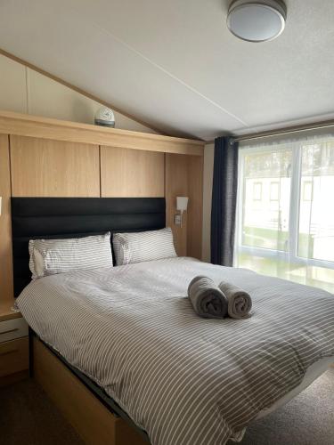 a bedroom with a large bed with two towels on it at 2 Bed Lake Front Van, Hoburne Holiday Park in Gloucestershire