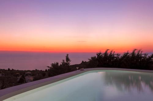 a swimming pool with a sunset in the background at Boo Premium Living Villen Auf Lefkada in Tsoukaladhes