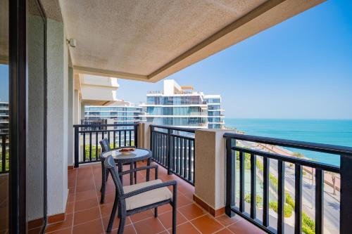 a balcony with a table and chairs and the ocean at Luxe Getaways Royal Amwaj Palm Jumeirah Resort Apartment Holiday Home in Dubai