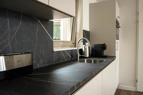 a kitchen with a black counter top and a sink at Kooparc vakantiepark in Giesbeek