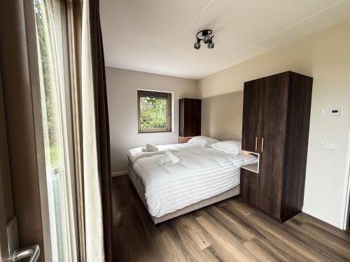a bedroom with a bed and a wooden cabinet at Kooparc vakantiepark in Giesbeek
