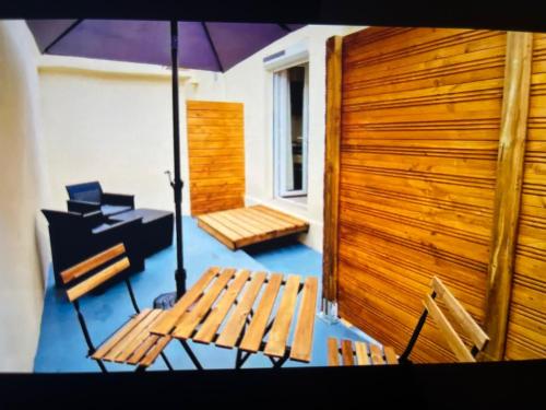une terrasse avec un banc, un parasol et un grill dans l'établissement Studio climatisé aux plages 1, à Sète