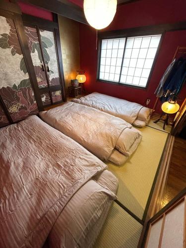 a bedroom with three beds and a window at sukeemon in Biei