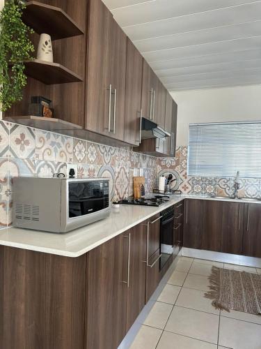 a kitchen with wooden cabinets and a microwave at Ubuntu Escape in Windhoek