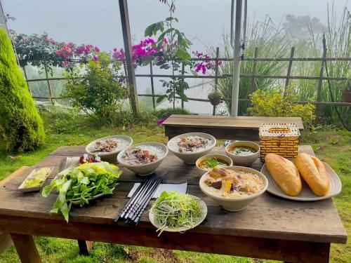 a picnic table with bowls of food on it at Mây Glamping in Xuân Thọ