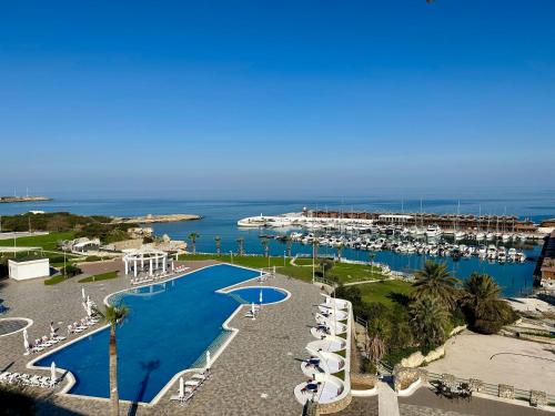 a resort with a pool and a marina with boats at Jasmine Court Hotel & Casino in Kérynia