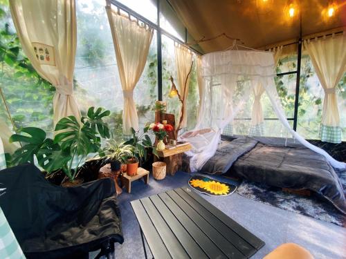a bedroom with a bed in a tent with plants at Mây Glamping in Xuân Thọ