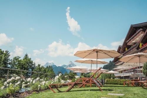 a group of tables with umbrellas in the grass at ERMITAGE Wellness- & Spa-Hotel in Gstaad