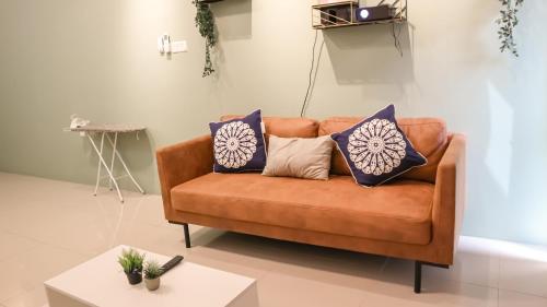 a brown couch with pillows on it in a living room at Ipoh The Cove Hillside Stay 7 to 10 pax, 5 min to Ipoh Town in Ipoh