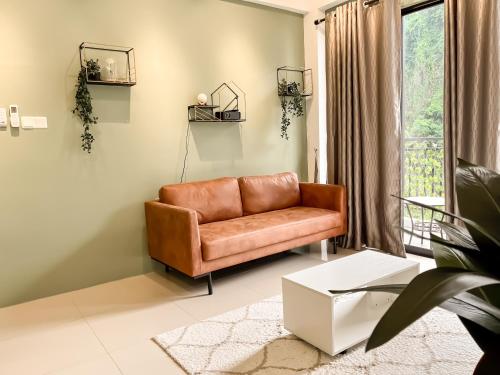 a brown leather couch in a living room with a window at Ipoh The Cove Hillside Stay 7 to 10 pax, 5 min to Ipoh Town in Ipoh