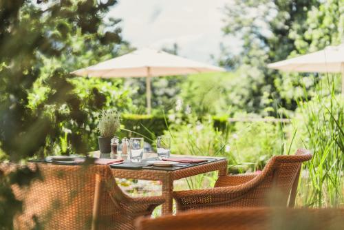 an outdoor table with glasses and an umbrella at ERMITAGE Wellness- & Spa-Hotel in Gstaad