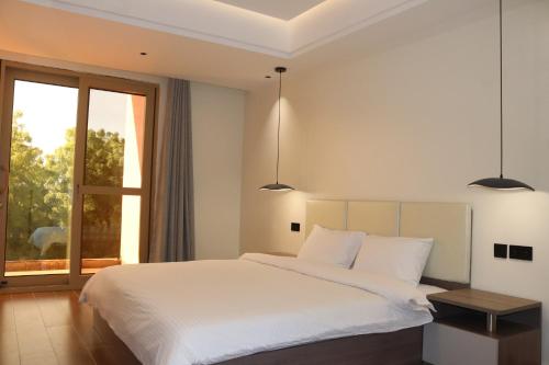 a bedroom with a large white bed and a window at Palatial Luxury Hotel and Apartment Juba in Juba