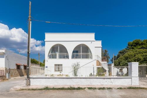 a white house with a fence in front of it at Sunset Torre Ovo by BarbarHouse in Torre Ovo