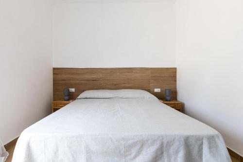 a bedroom with a white bed with a wooden headboard at Sunset Torre Ovo by BarbarHouse in Torre Ovo