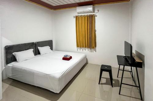 a bedroom with a white bed and a television at RedDoorz Syariah at Humaira Stay Tabalong in Tanjung