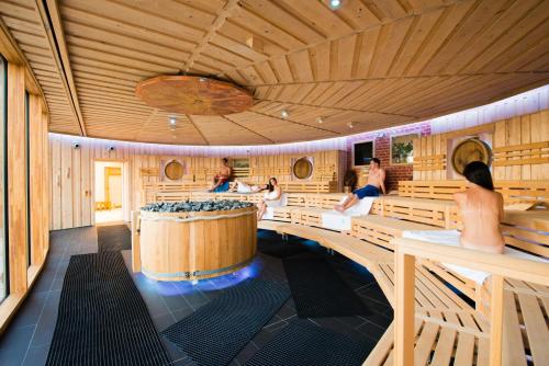 a sauna with a tub and people sitting in it at Ferienhaus Sanddornweg an der Therme Obernsees in Truppach