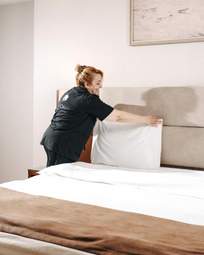 a woman making a bed in a bedroom at Hotel Diamond in Baku
