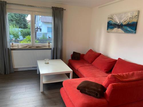 a living room with a red couch and a table at Ferienwohnung Bianca in Ettenheim